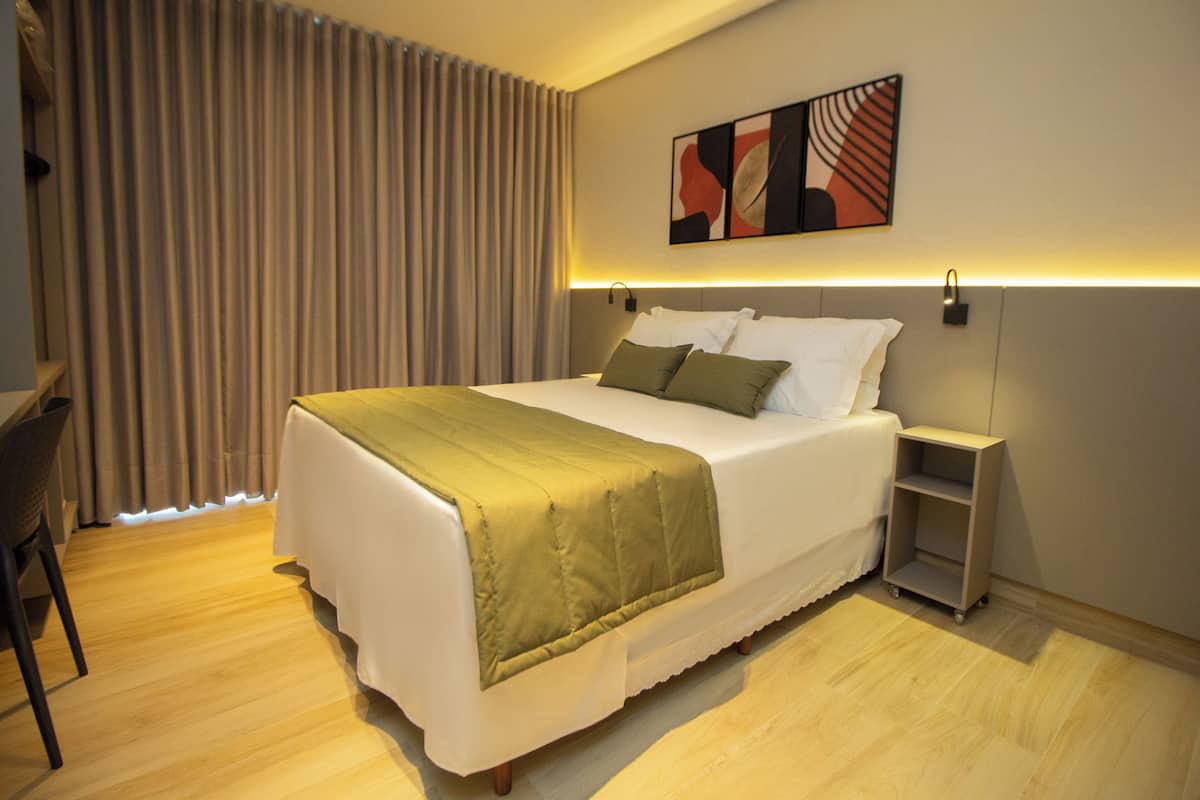 A modern hotel room with a large bed, a desk, and a chair.