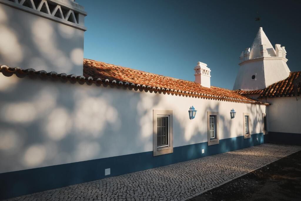 Een gebouw met pannendak, een wit- en blauwe gevel en een straatje van keien.