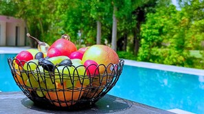 A fruit basket filled with apples and oranges placed on a table by a poolside. - Maharana Palace by Asapian Hotels (Amer)