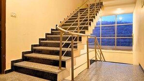 A staircase with metal handrails and a window with a view of trees. - Maharana Palace by Asapian Hotels (Amer)