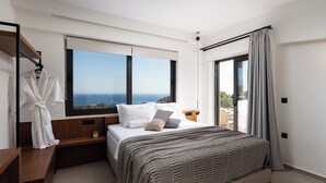 A modern bedroom with a large bed, a view of the sea, and a balcony.