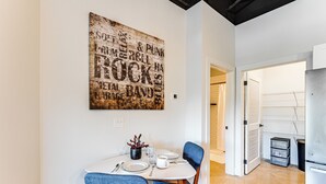 Ein Essbereich mit rustikaler Wandgestaltung, einem weißen Tisch und blauen Stühlen.
