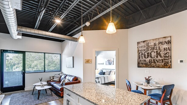 Eine moderne Küche mit Granitarbeitsplatten, ein Essbereich mit Tisch und Stühlen sowie ein Wohnbereich mit Sofa und Couchtisch.