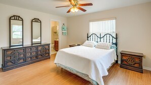 A bedroom with a bed, dresser, and a ceiling fan.