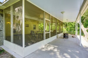Une terrasse couverte avec une table et des chaises, un ventilateur de plafond et un mur en pierre.