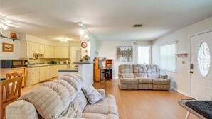 A spacious living area with a sofa, a dining table, and a kitchen in the background.