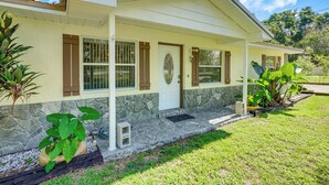 A two-story house with a stone foundation, a covered porch, and a front door with a decorative glass panel.