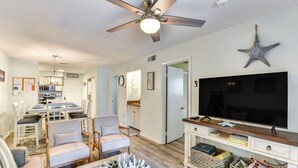 A living room with a ceiling fan, a flat-screen TV, and a starfish decoration on the wall. - 1/2 Mi to Folly Field Beach: Condo w/ 2 Pools (Hilton Head Island)