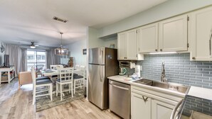 A modern kitchen with stainless steel appliances, white cabinetry, and a blue-tiled backsplash. - 1/2 Mi to Folly Field Beach: Condo w/ 2 Pools (Hilton Head Island)