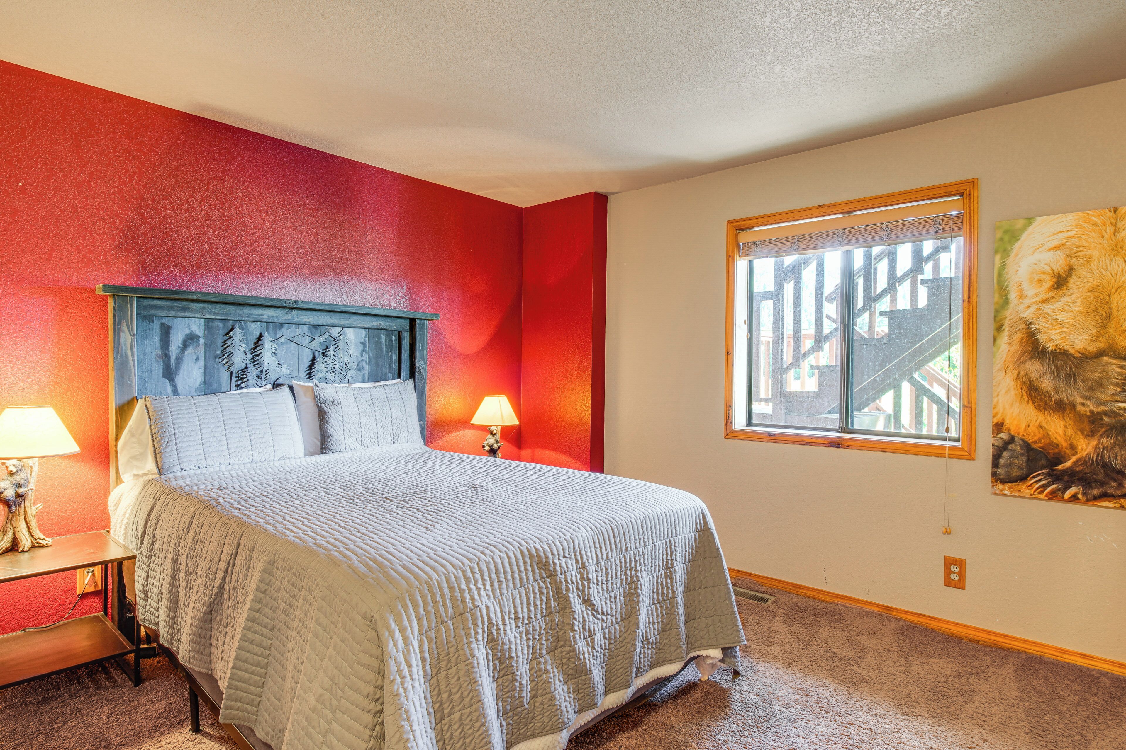 A bedroom with a bed, nightstands, a window, and a painting on the wall.