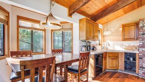 Une cuisine spacieuse avec des meubles de rangement en bois, une table à manger avec des chaises et un mur décoratif en briques.