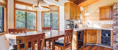 Una cocina amplia con armarios de madera, una mesa de comedor con sillas y una pared decorativa de ladrillo.