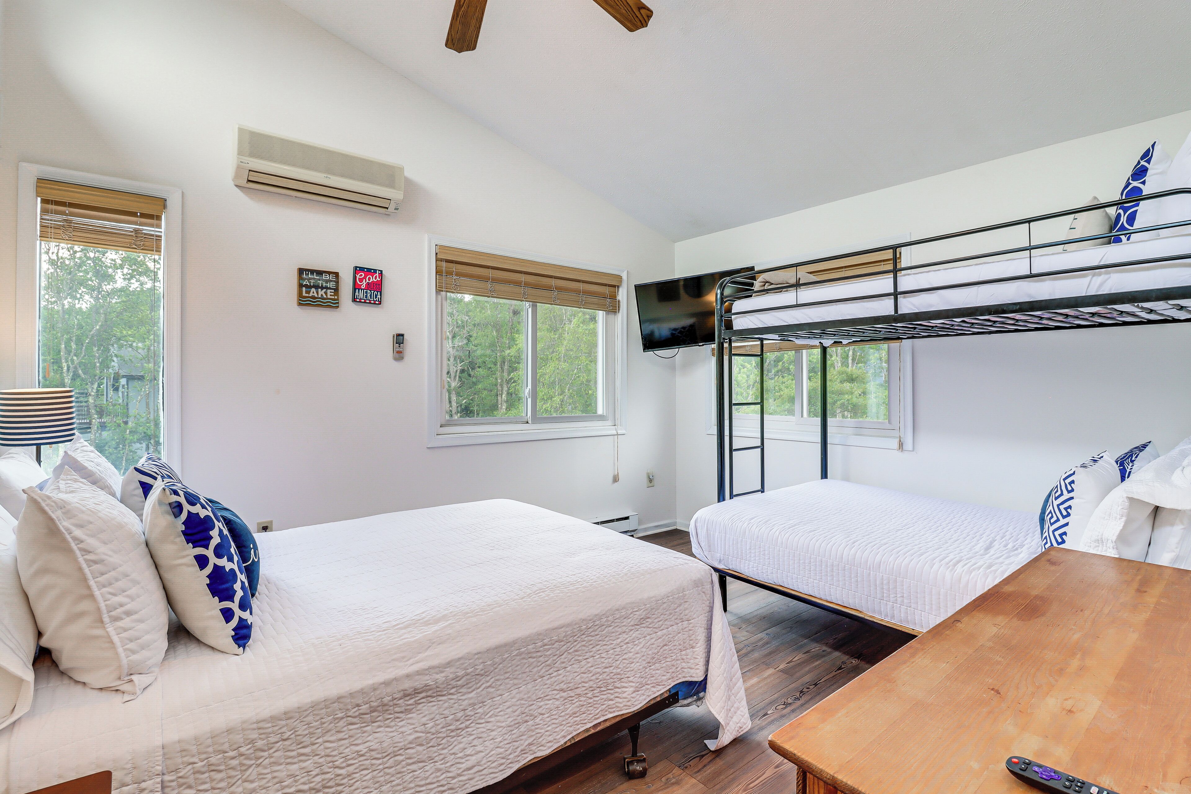 A room with two beds, a wooden table, and a TV mounted on the wall.