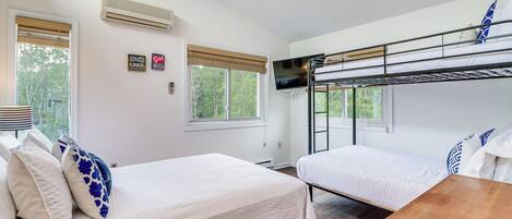 A room with two beds, a wooden table, and a TV mounted on the wall.