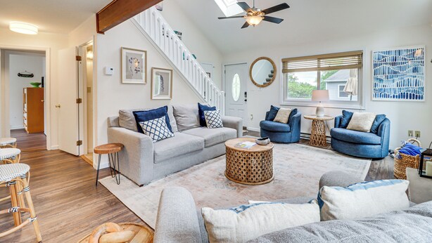 A spacious living room with a high ceiling, a ceiling fan, a staircase, and a large window providing natural light. - Spacious Family Retreat: Pocono Home w/ Deck (Albrightsville)