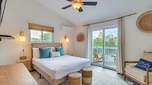A bedroom with a bed, bedside tables, a ceiling fan, a window with blinds, a balcony with a chair, and a woven rug. - Spacious Family Retreat: Pocono Home w/ Deck (Albrightsville)