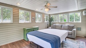 A bedroom with a bed, a green nightstand, a gray sofa, and large windows. - Spacious Family Retreat: Pocono Home w/ Deck (Albrightsville)
