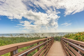 A wooden boardwalk leading to a beach with a clear sky and clouds. - Oceanfront Fort Pierce Condo: Pool & Beach Access! (Fort Pierce)