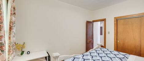 Een slaapkamer met een bed, een bureau, een stoel en een deur.