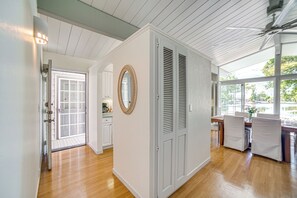 Une pièce dotée de planchers en bois, de murs blancs, d’un grand miroir et d’un coin repas avec une table et des chaises.