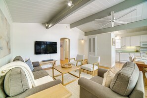 Un salon moderne comprenant un canapé, des fauteuils, une table basse et un téléviseur.