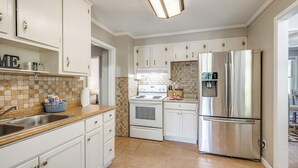 Une cuisine moderne avec des meubles blancs, un réfrigérateur en acier inoxydable, un four double et un revêtement mural en carreaux.
