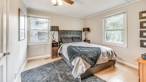 Une chambre à coucher avec un lit, un ventilateur de plafond, deux tables de chevet et une fenêtre.
