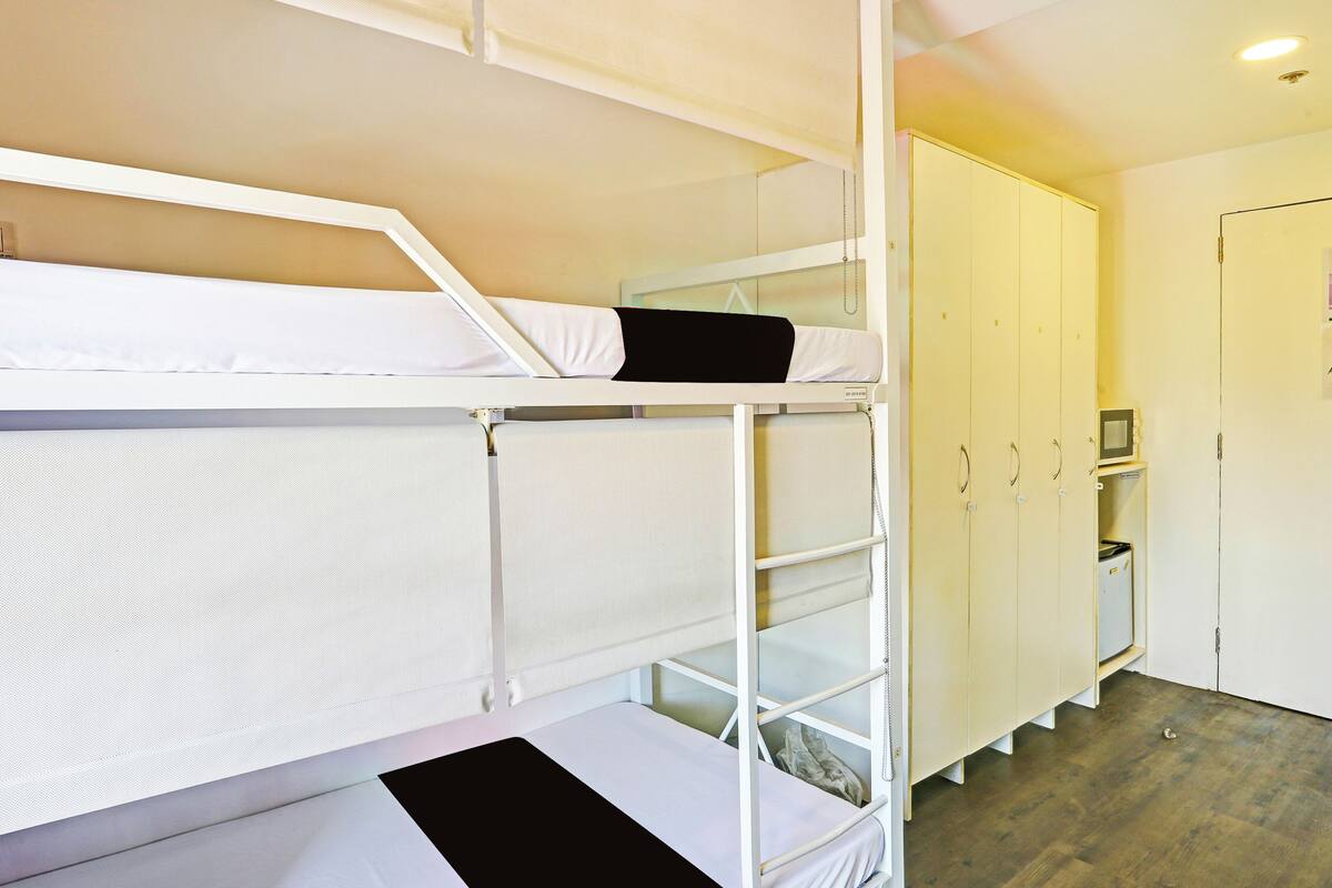 A bunk bed room with a wardrobe and a small desk.