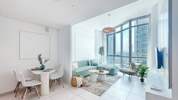Un salon moderne doté d’une grande fenêtre, d’un canapé, d’une table basse et d’un coin repas avec des chaises et une table.