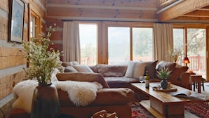 A cozy cabin interior with a wooden interior, a sofa, a coffee table, and a vase with flowers. - Hillside Cabin - Mt Views - Patio Decks - Hot Tub (Cascade)