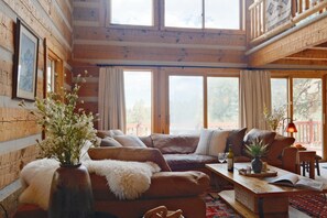 A cozy cabin interior with a wooden interior, a sofa, a coffee table, and a vase with flowers. - Hillside Cabin - Mt Views - Patio Decks - Hot Tub (Cascade)