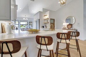 A modern kitchen with white cabinetry, a large island, and bar stools.