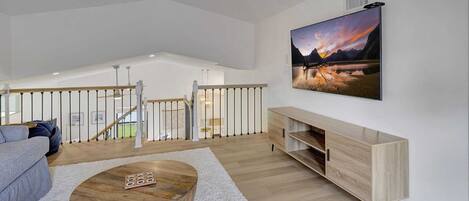 Un salon spacieux avec une table basse en bois, un canapé gris et un meuble TV en bois.