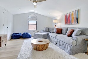 Una sala de estar moderna con un sofá gris, una mesa de centro redonda de madera y una alfombra blanca.