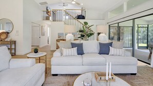 Un salon spacieux avec un grand canapé, une table basse et un escalier menant à l’étage supérieur.