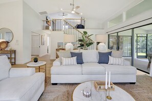 A spacious living room with a large sofa, a coffee table, and a staircase leading to an upper level.