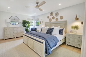 A bedroom with a bed, a dresser, a mirror, a ceiling fan, and decorative wall art. - Luxury, Privacy and Close to Beach (Bonita Springs)