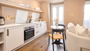 A modern kitchen with white cabinets, a built-in oven, and a dining area with a round table and two chairs. - St Johns Wood Terrace Retreat (London)