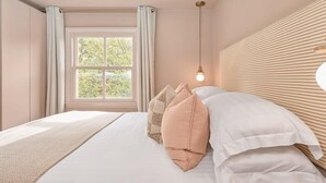 A bedroom with a large bed, a window with curtains, and a wall-mounted light fixture. - St Johns Wood Terrace Retreat (London)