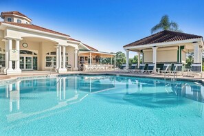 En swimmingpool med liggestole og et overdækket siddeområde.