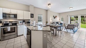 A modern kitchen with white cabinets, stainless steel appliances, and a granite countertop.