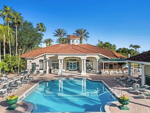 Un resort con piscina, sillones de descanso y palmeras.