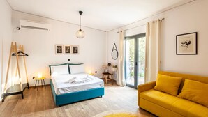 Een slaapkamer met een bed, een gele bank, een bureau en een raam met gordijnen.