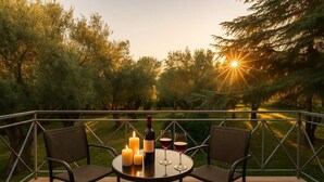 Een terras met een tafel gedekt voor twee personen, met kaarsen en wijnglazen.