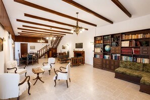 Un salón espacioso con chimenea, una estantería y una escalera que conduce a otro nivel.