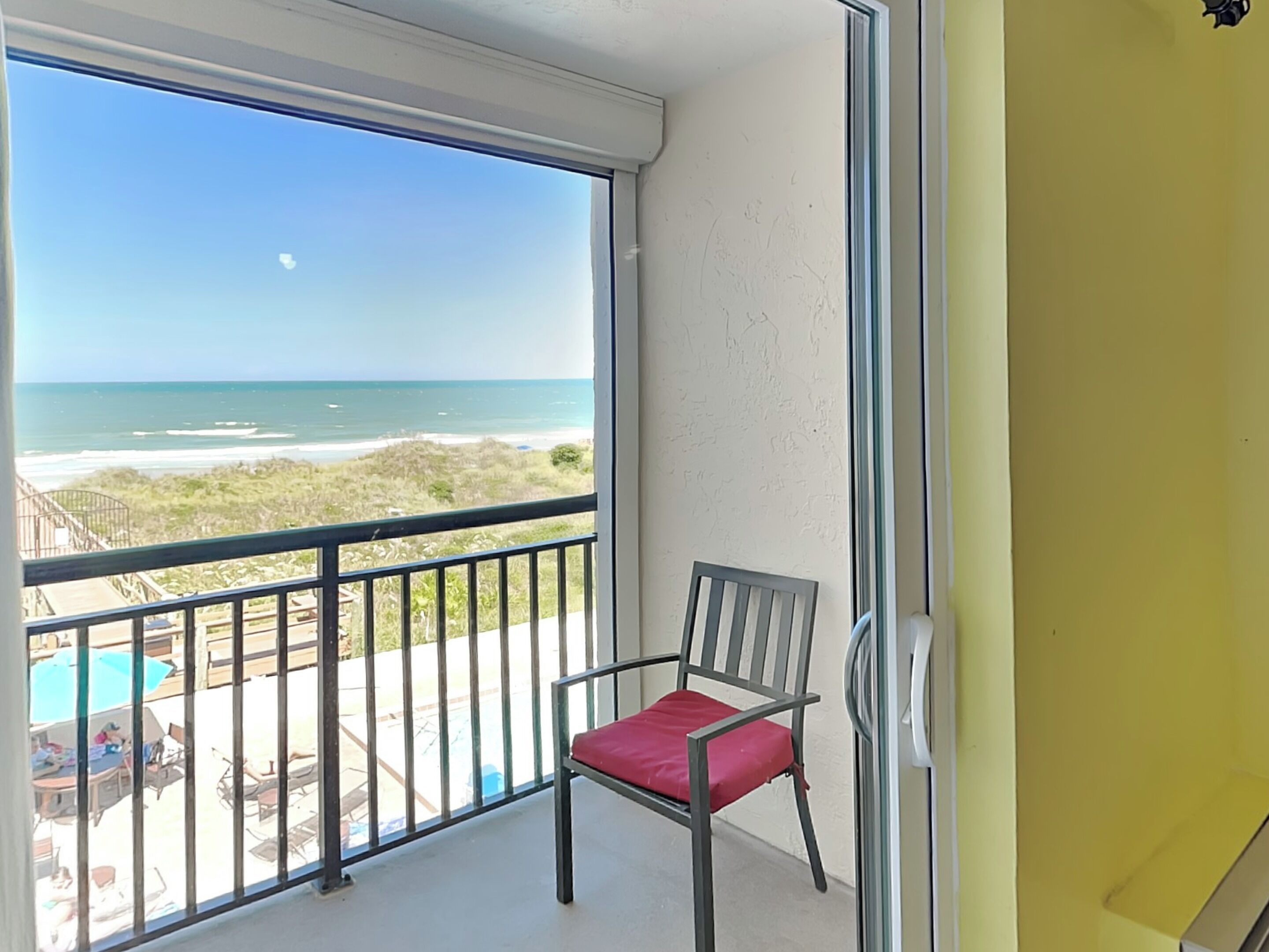 A balcony with a view of the beach and ocean.