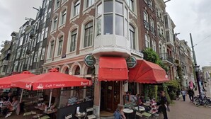 Un edificio en esquina con varios toldos rojos y un cartel de 'Heineken'.
