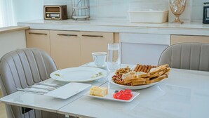 Une table à manger dressée avec des assiettes, des couverts, une carafe d’eau et des plats.