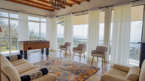 Un salon spacieux avec une table de baby-foot, deux fauteuils et une grande fenêtre offrant une vue sur les montagnes.
