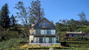 Une maison moderne à deux étages, dotée de grandes fenêtres, d’un balcon et d’un jardin.